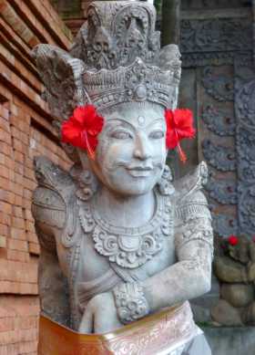 Indonésie Bali île art beauté Statue hindoue parée de fleurs d'hibiscus et d'une ceinture en tissu