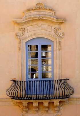 Méditerranée Italie Sicile Noto fenêtres balcons Mur crème, rembarde galbée, fenêtre pompeuse, reflet du monument d'en face dans les vitres 