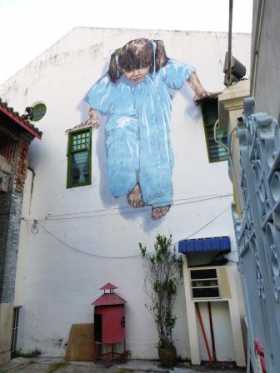 Penang 3 une des vedettes du street art de George Town, la kung fu girl, s'appuie sur les éléments d'architecture, les fenêtres