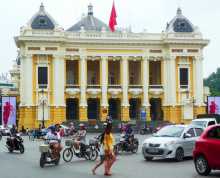 Une femme et sa fille traversent entre motos et scooters en plein milieu de la place de l'Opéra à Hanoi au Vietnam 